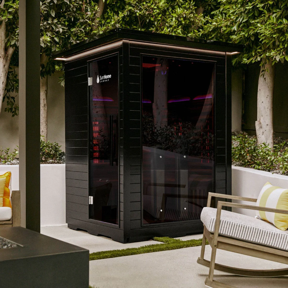 Modern black sauna cabin in a serene backyard setting.