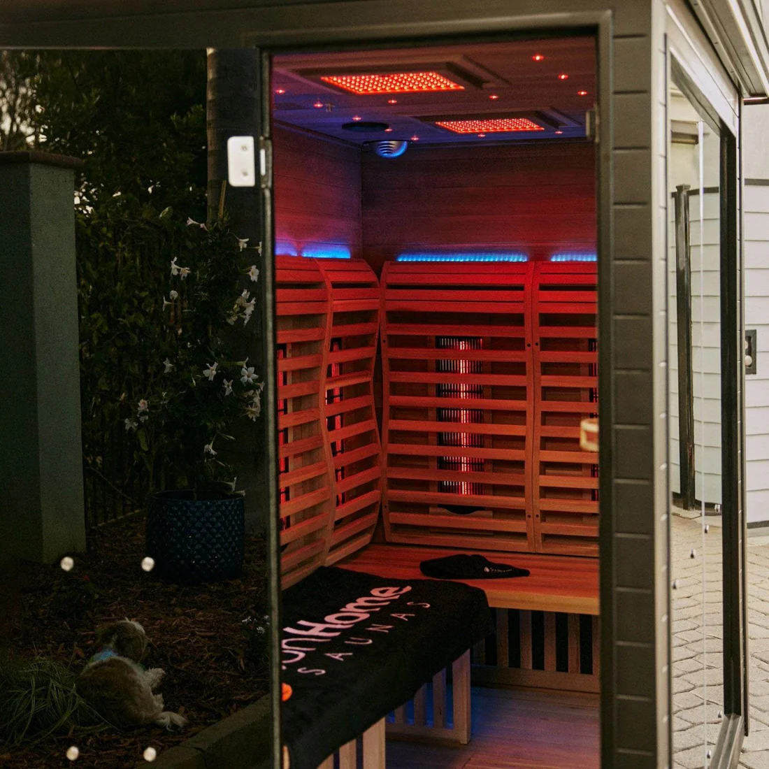 Modern infrared sauna with wooden interior and glowing red lights.