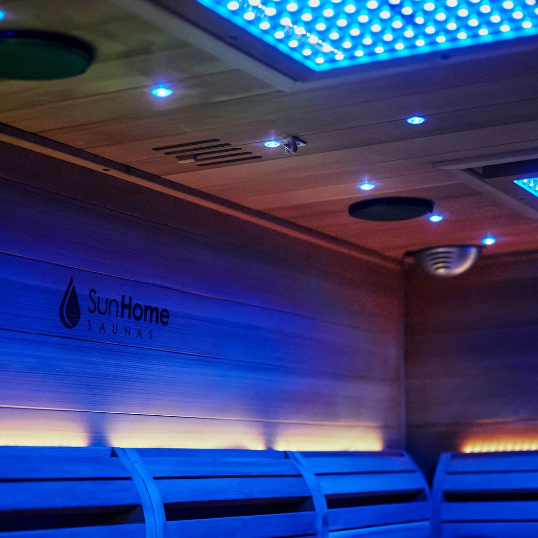 Interior of a modern sauna with blue LED lighting and wooden benches.