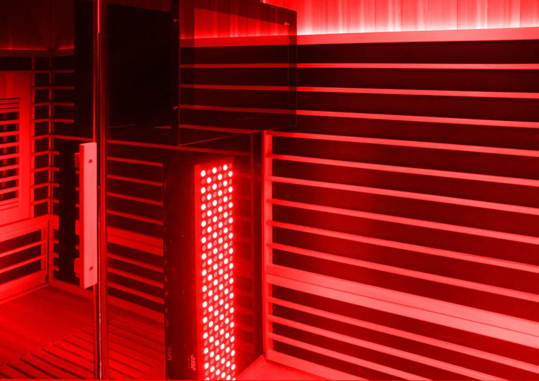Red-lit infrared sauna with wooden benches and glowing panels.