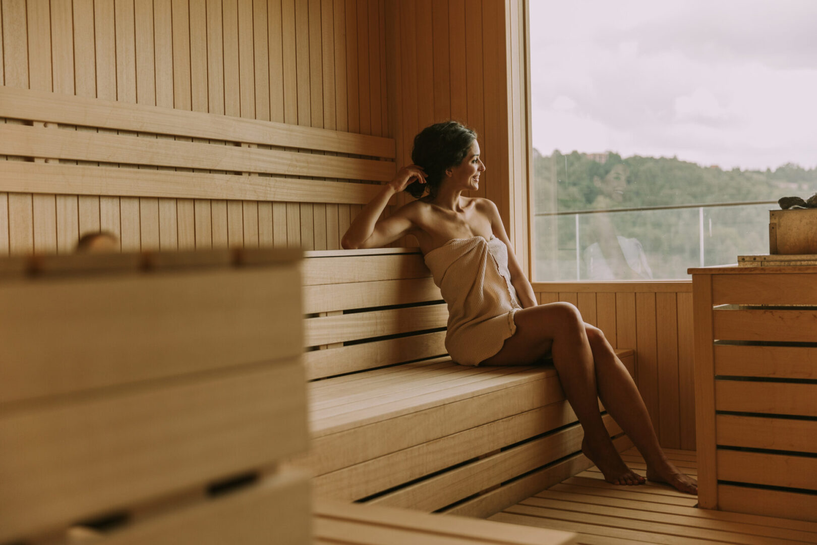 Woman relaxing inside a wooden sauna, enjoying the warmth.
