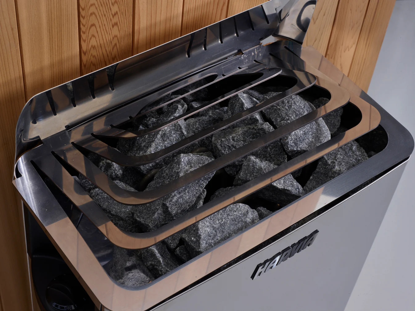 A sauna heater with hot stones and metal guard rails.
