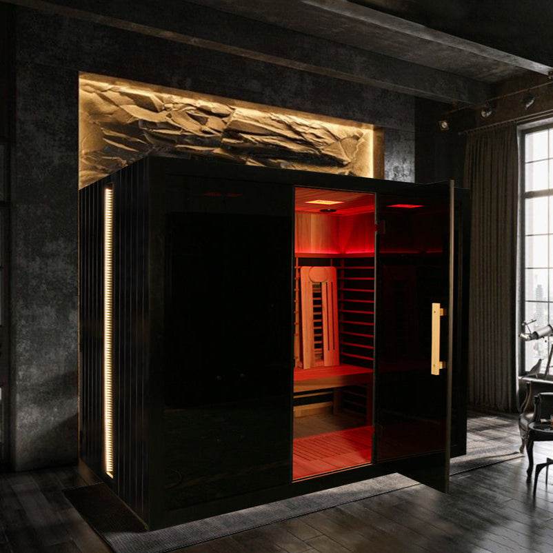 Modern infrared sauna with sleek black and red interior in a dim room.