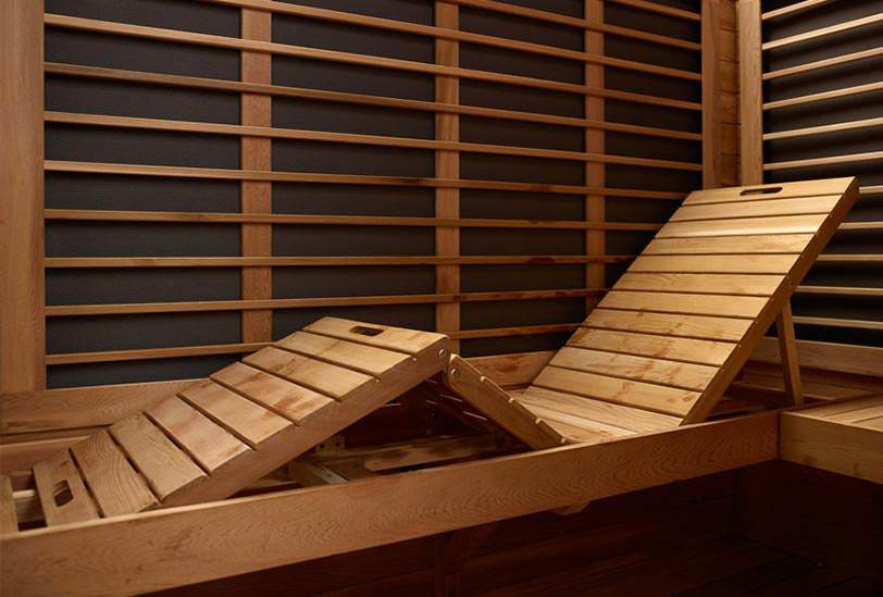 Two wooden lounge chairs with slatted design in a warm-toned room.