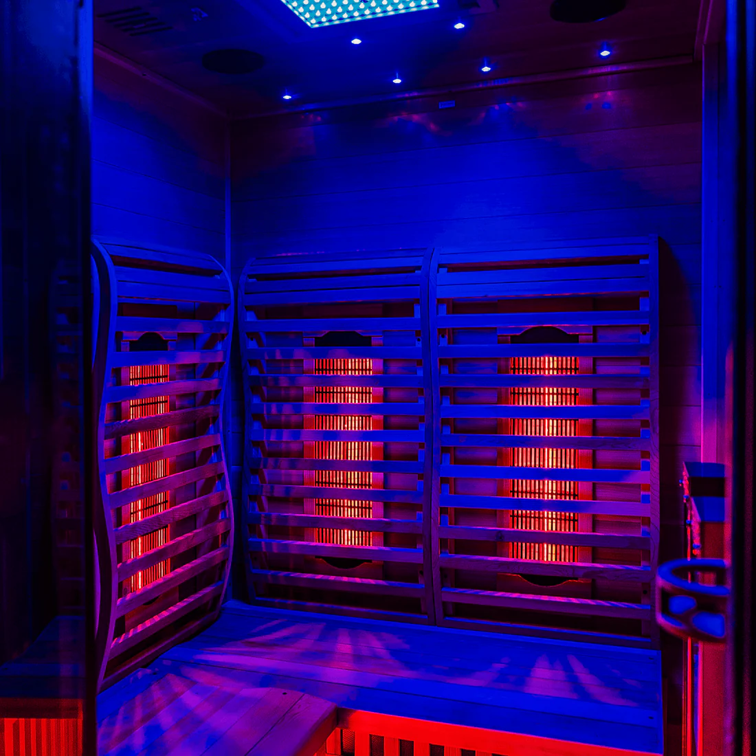 A modern infrared sauna room with glowing red panels and blue ambient lighting.