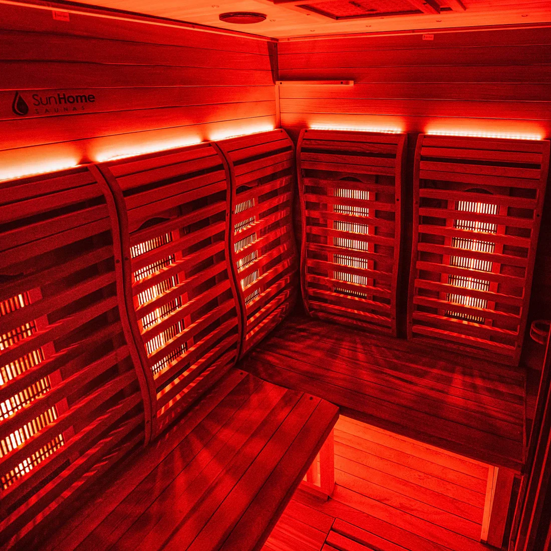Cozy infrared sauna room with warm red lighting and wooden benches.