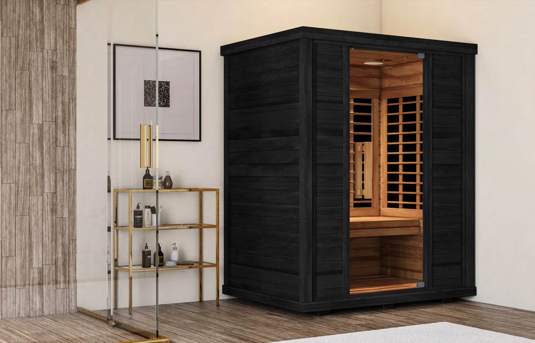 Modern black wooden sauna with glass door in a cozy room corner.