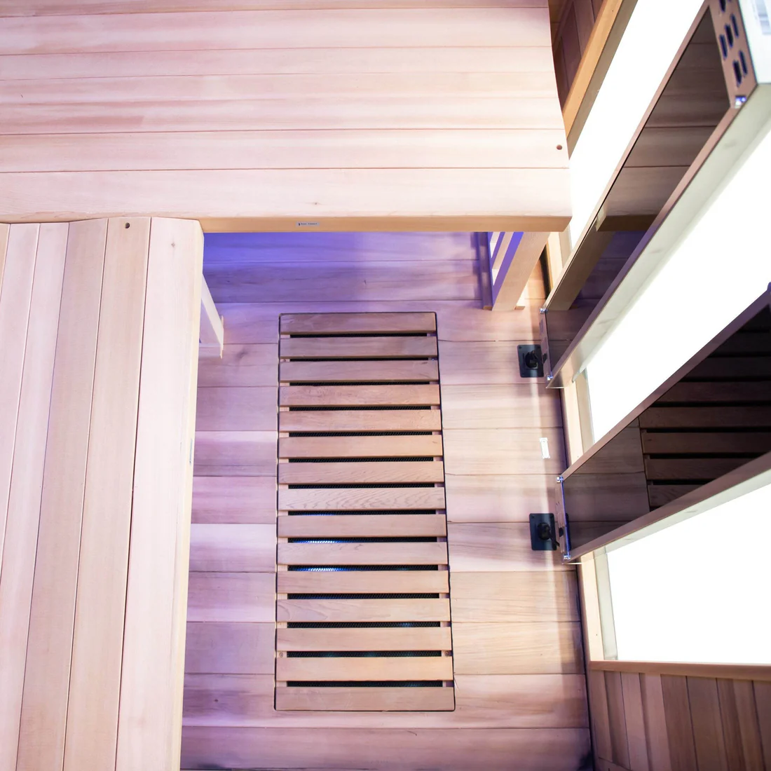 Modern sauna interior with wooden benches and a heater.