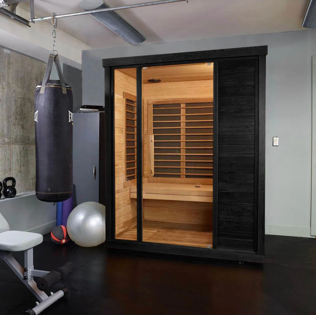 A modern home sauna with glass door in a workout room.