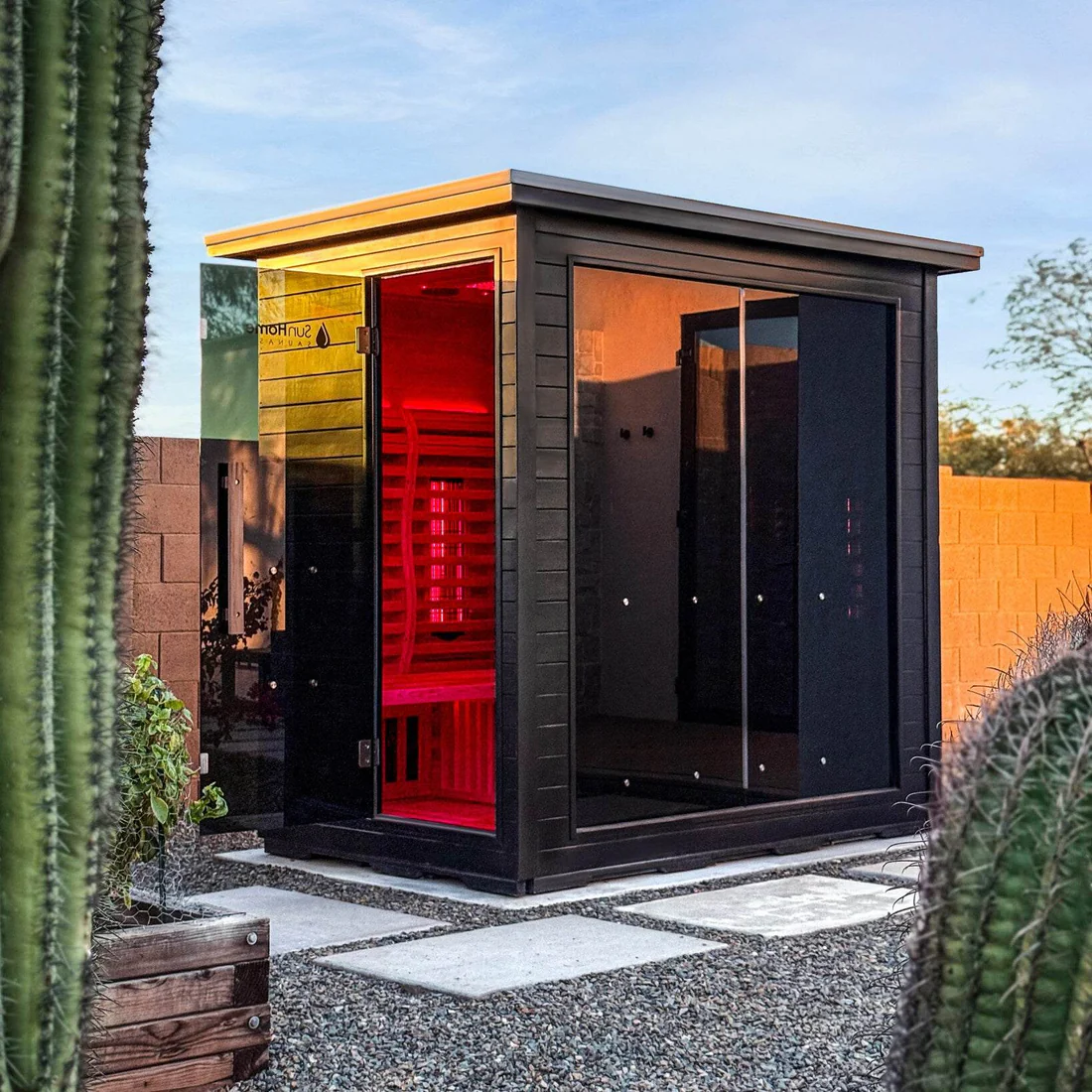 Modern outdoor sauna with glass walls and wooden accents.