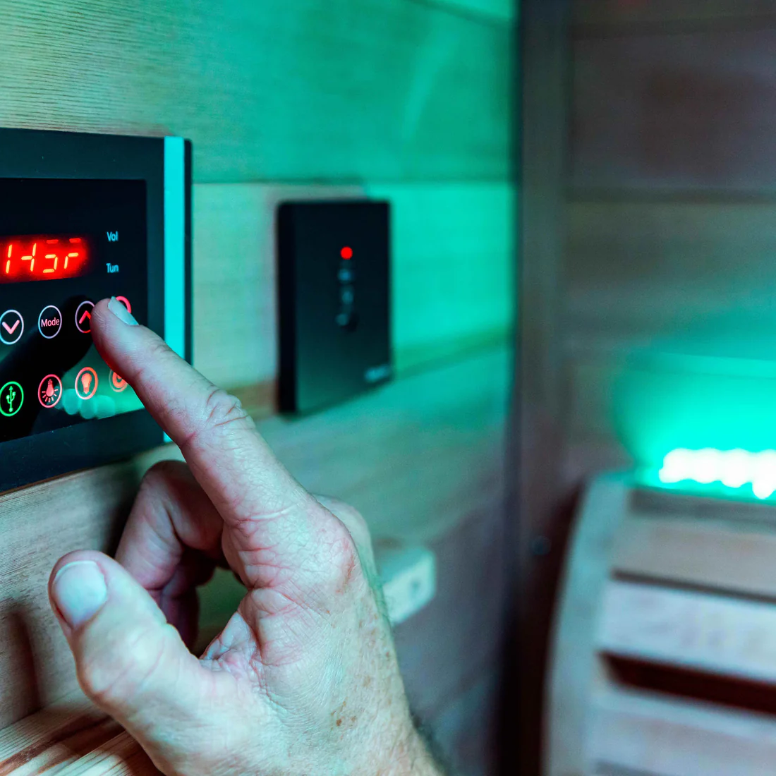 Person pressing a button on a sauna control panel.