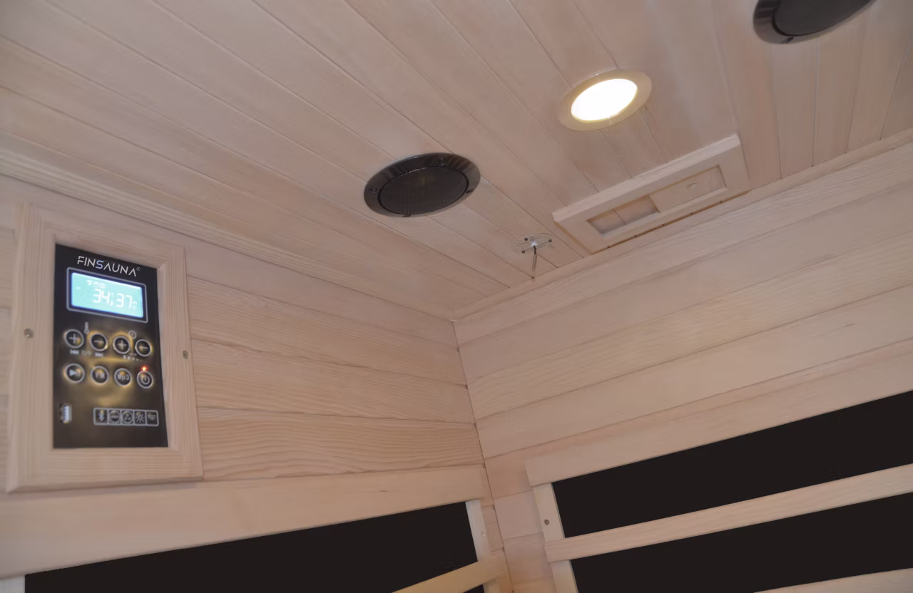 Ceiling of a wooden sauna with a light and speaker.