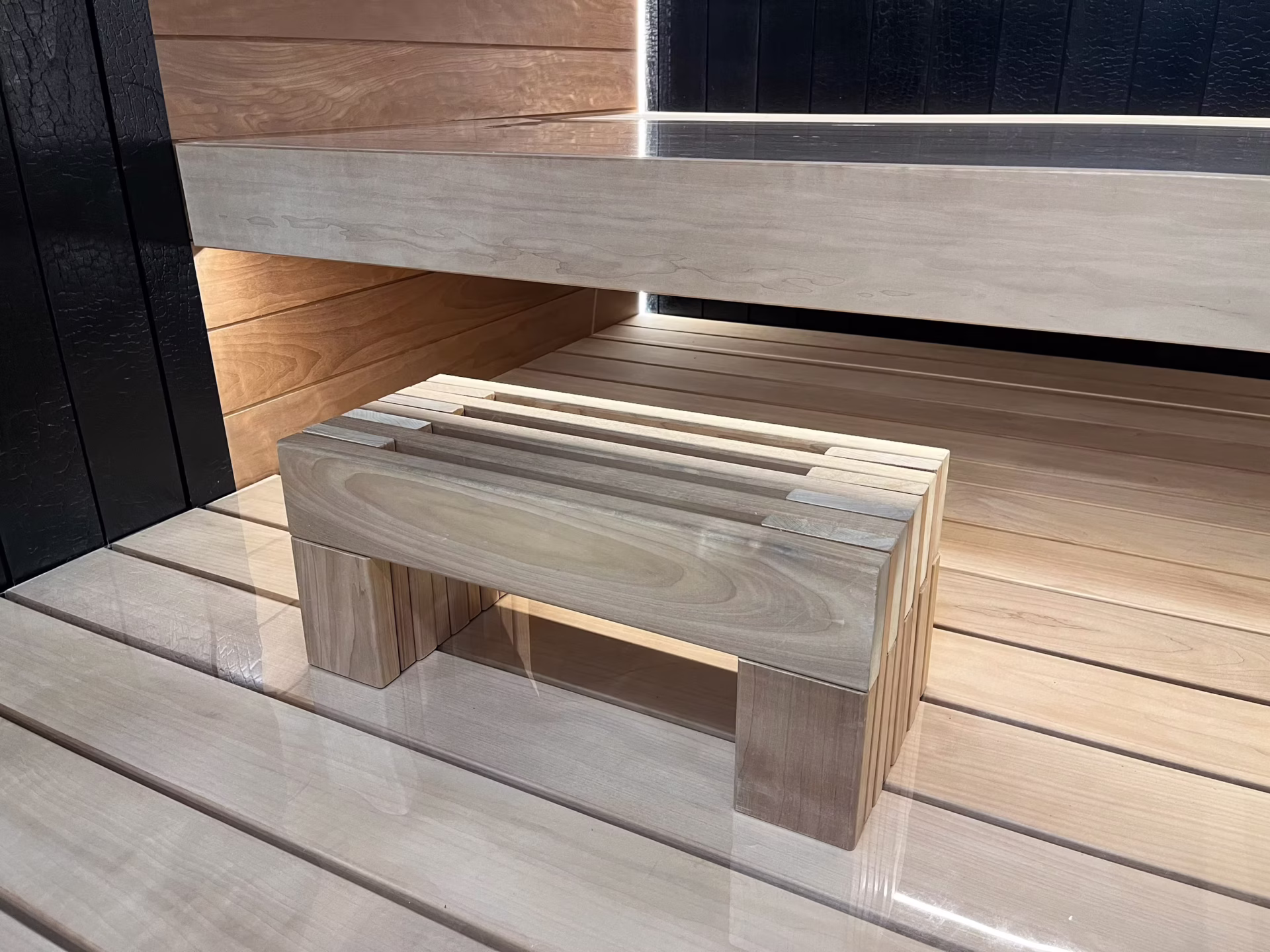 Minimalist wooden stool with a natural finish on a wooden floor.