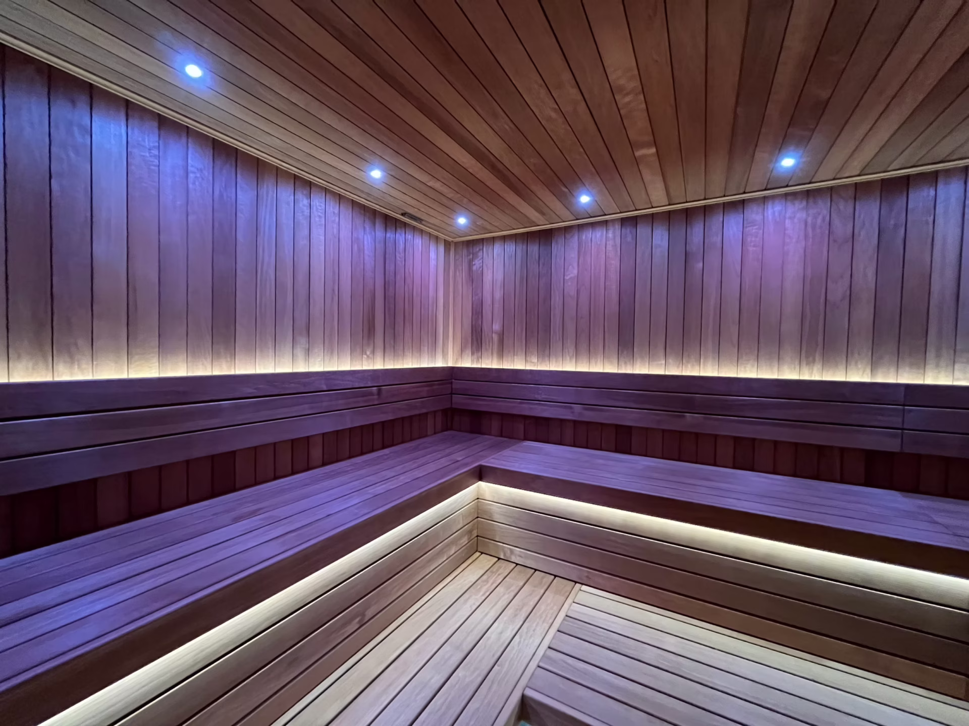 Modern wooden sauna room with ambient LED lighting.