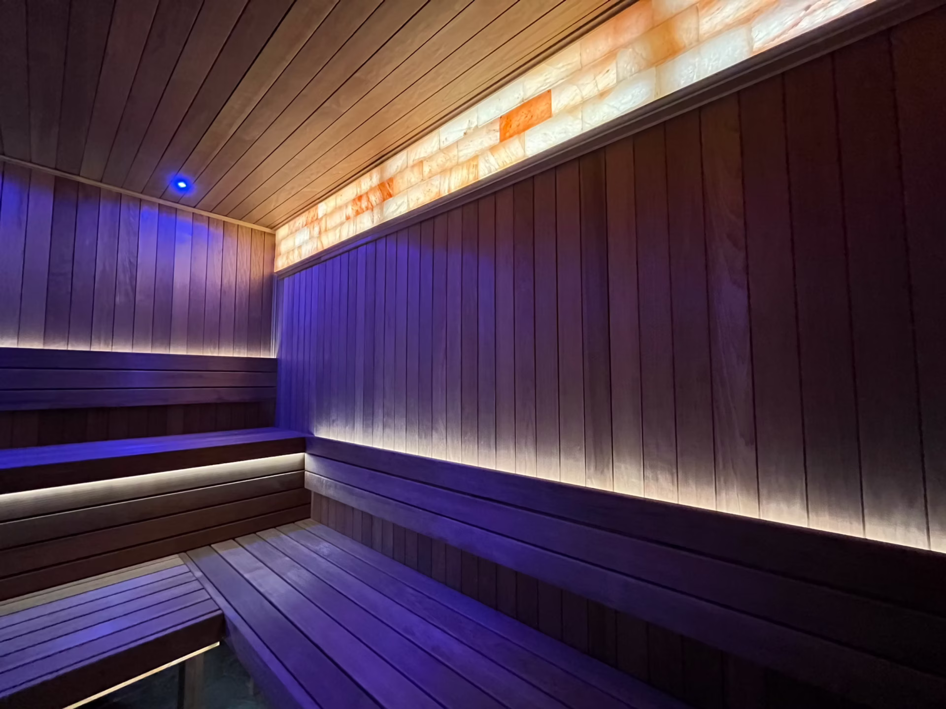 Modern sauna room with wooden benches and ambient lighting.
