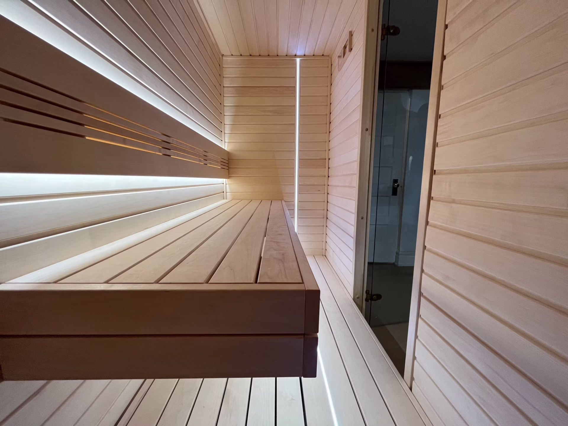 Modern wooden sauna interior with sleek bench and lighting.