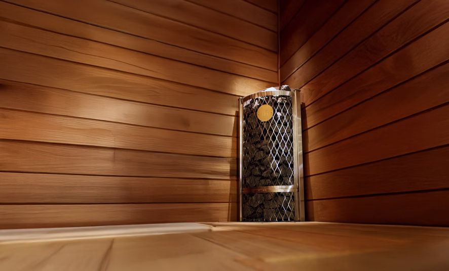 Cozy wooden sauna interior with a heater and stones.