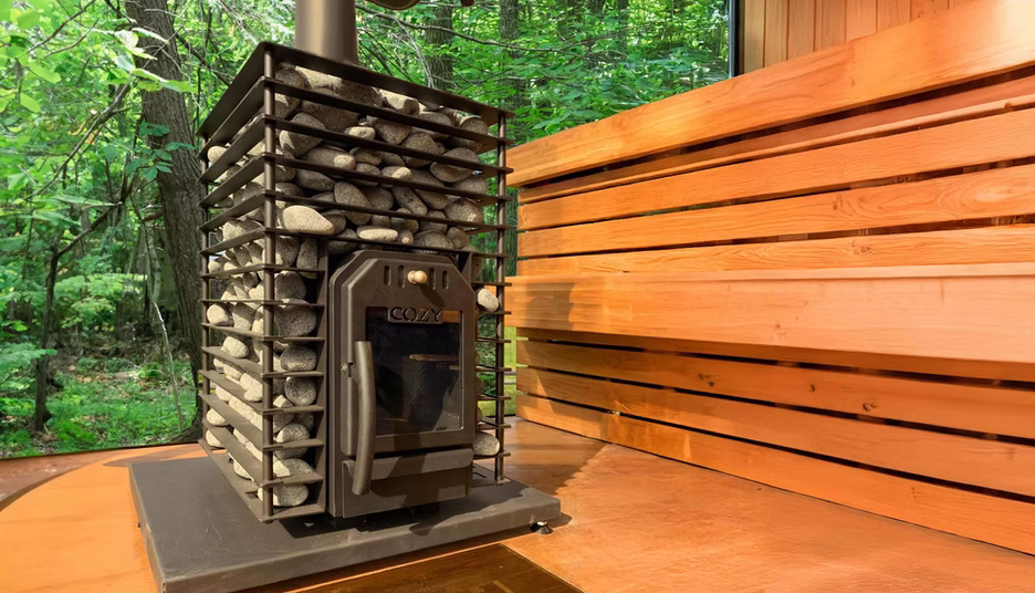 Cozy wooden sauna interior with a modern heater and stacked stones.