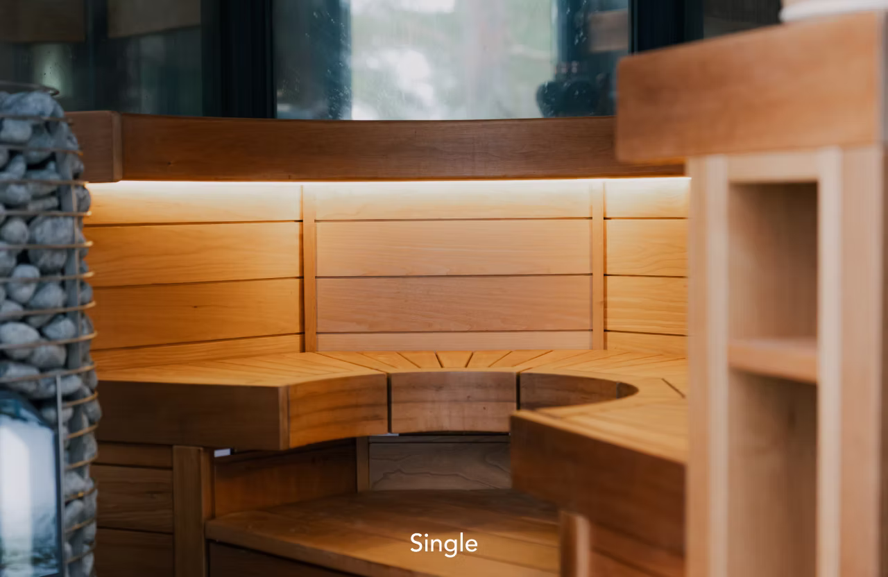 Cozy wooden sauna interior with warm lighting and curved bench seating.