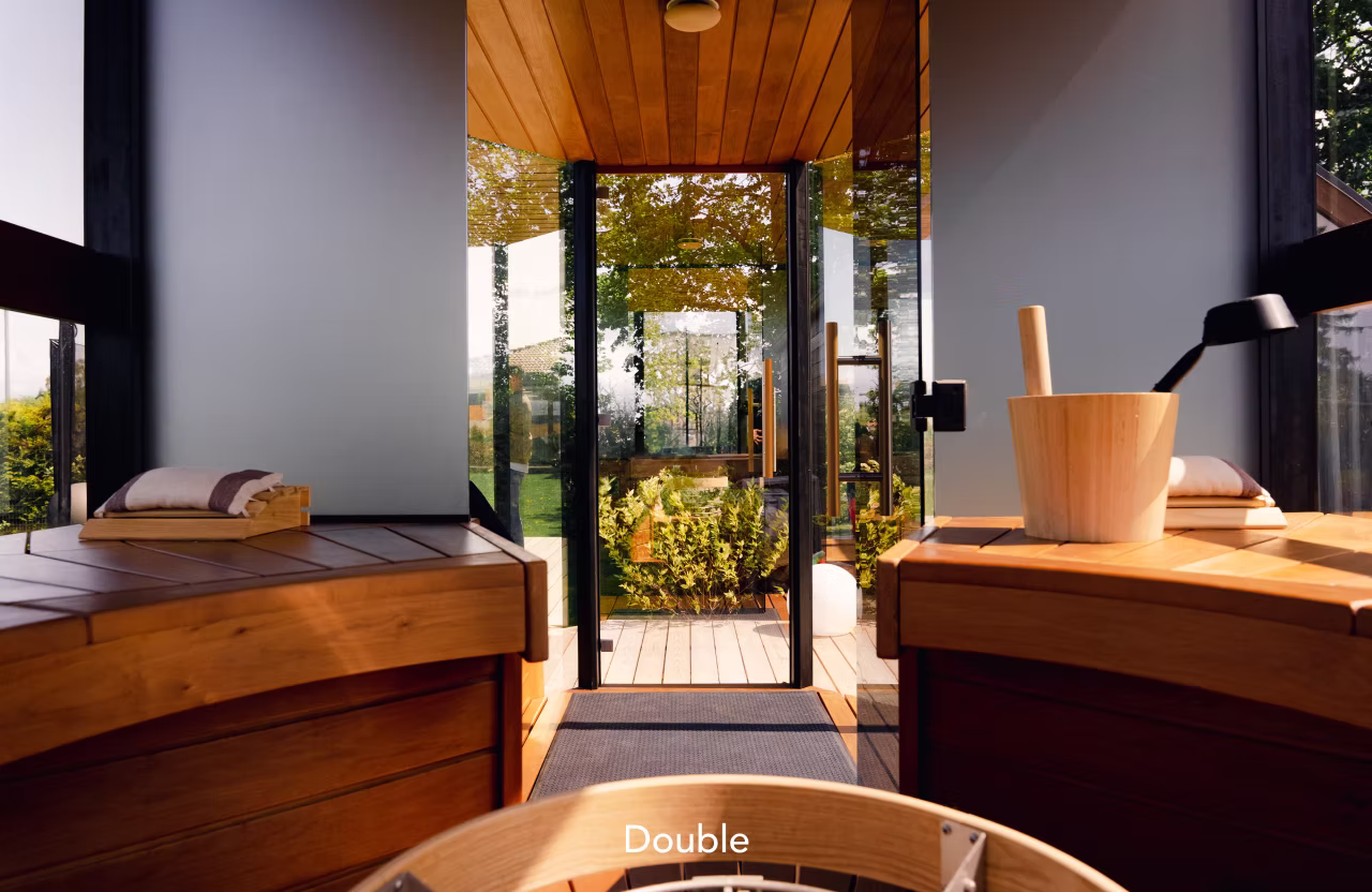 Cozy wooden sauna interior with glass door opening to a garden.