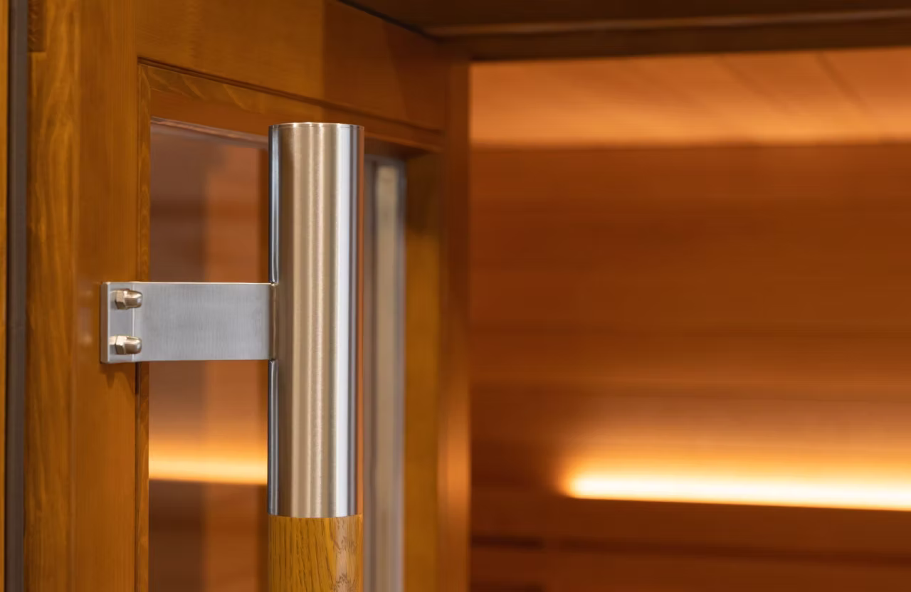 Close-up of a modern glass door handle with wooden interior background.